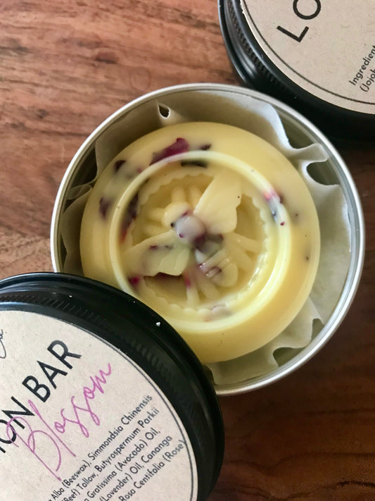 Solid lotion bar with rose petals, 2 oz circular puck with a honey bee shape on top, top view, handmade with tallow and beeswax